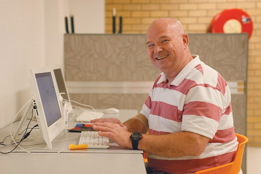 Happy, mature aged man learning how to use a computer during the CTA Class.