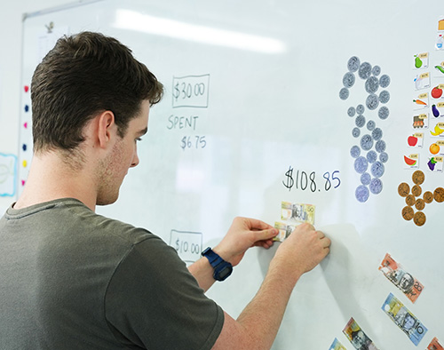 Person placing money on whiteboard.
