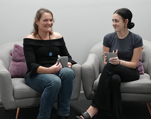 Two people holding coffee cups chatting